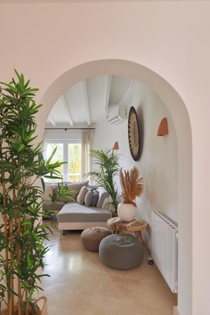 Un salon avec un canapé, une table basse, une plante en pot et une horloge murale.