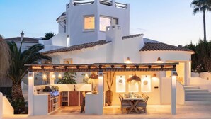 Une villa moderne dotée d’une piscine, d’un espace repas extérieur et d’un barbecue.