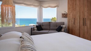 Une chambre avec un grand lit, un canapé et une vue sur la mer.