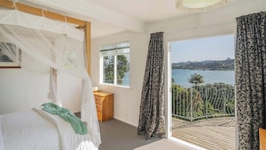 Ein Schlafzimmer mit einem Bett, einem kleinen Holztisch, einem Fenster und einem Balkon mit Meerblick.