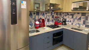 Una cocina moderna con un refrigerador de acero inoxidable, un microondas, una estufa a gas y un lavavajillas.