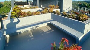 Un edificio moderno con techo plano, ventanas amplias y una pequeña turbina eólica.