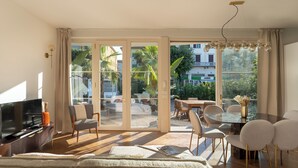 A modern living room with a flat-screen TV, a sofa, and a dining area with a glass table and chairs. - Casa Amare 4+2, Emma Villas (Camaiore)