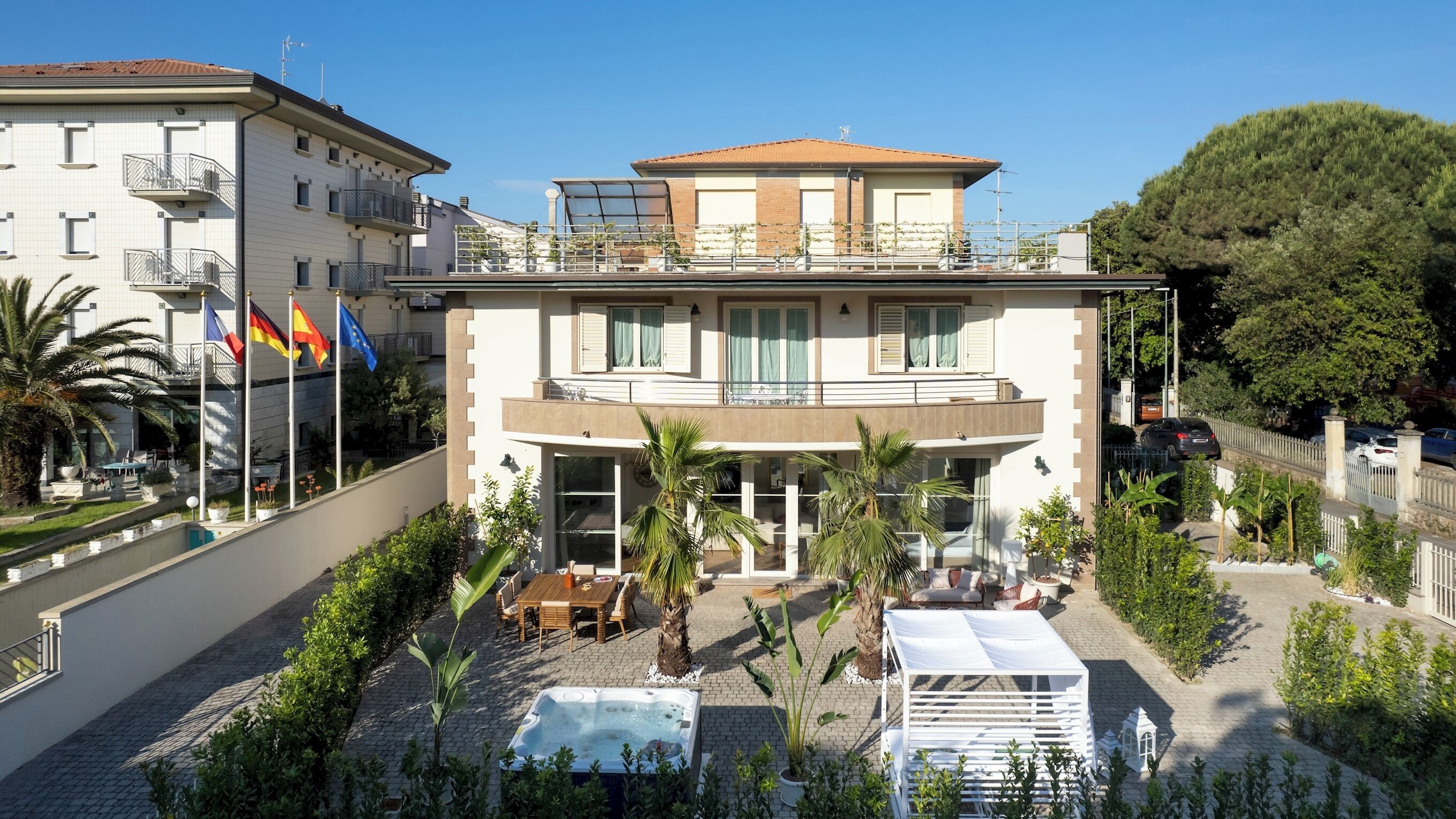 A two-story building with a balcony, a swimming pool, and a garden area.