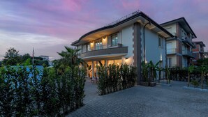 A modern multi-story building with a curved roofline, large windows, and a balcony. - Casa Amare 4+2, Emma Villas (Camaiore)