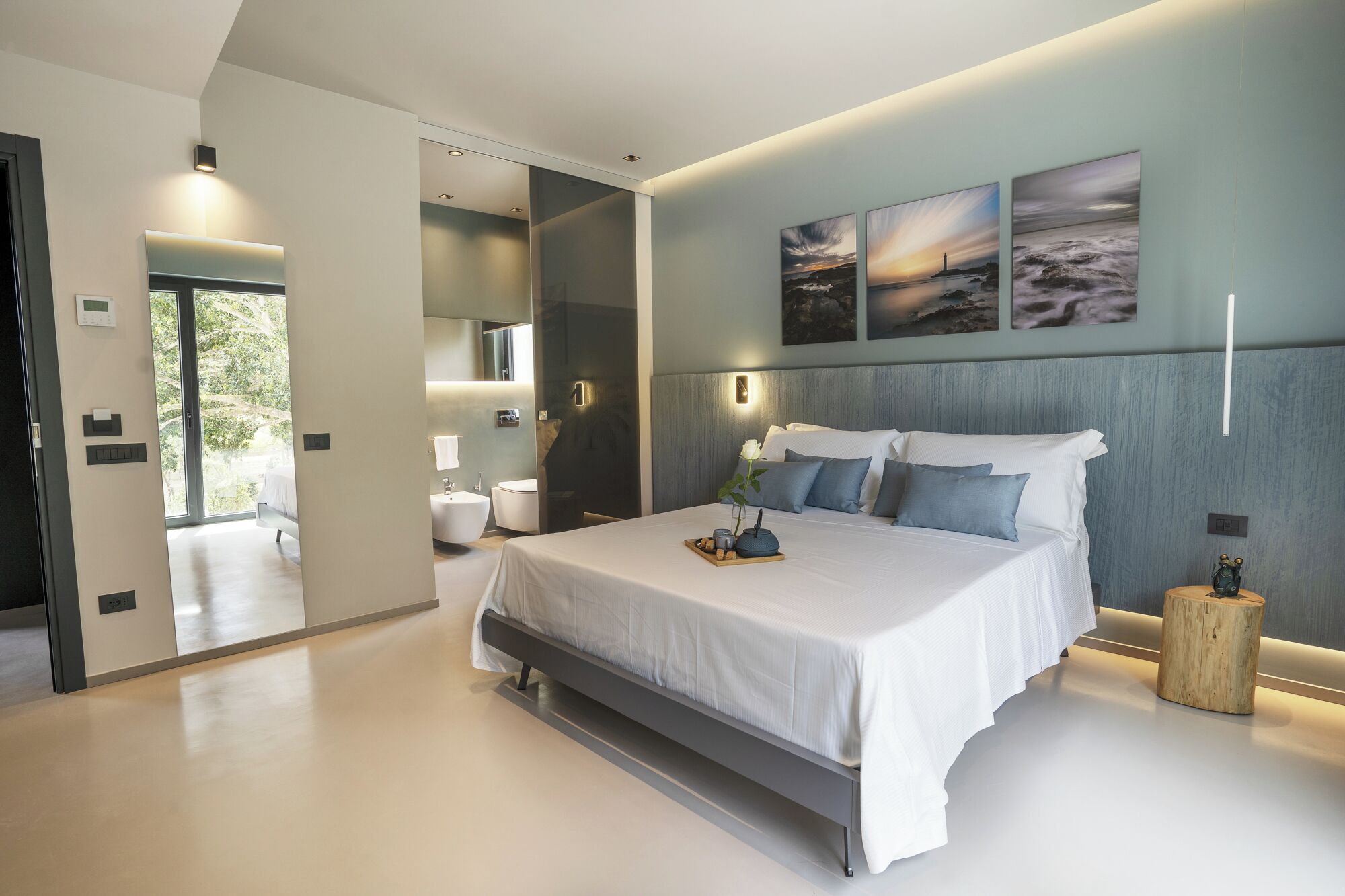 Une chambre moderne avec un grand lit, des tables de chevet, une commode et une vue sur la salle de bain.
