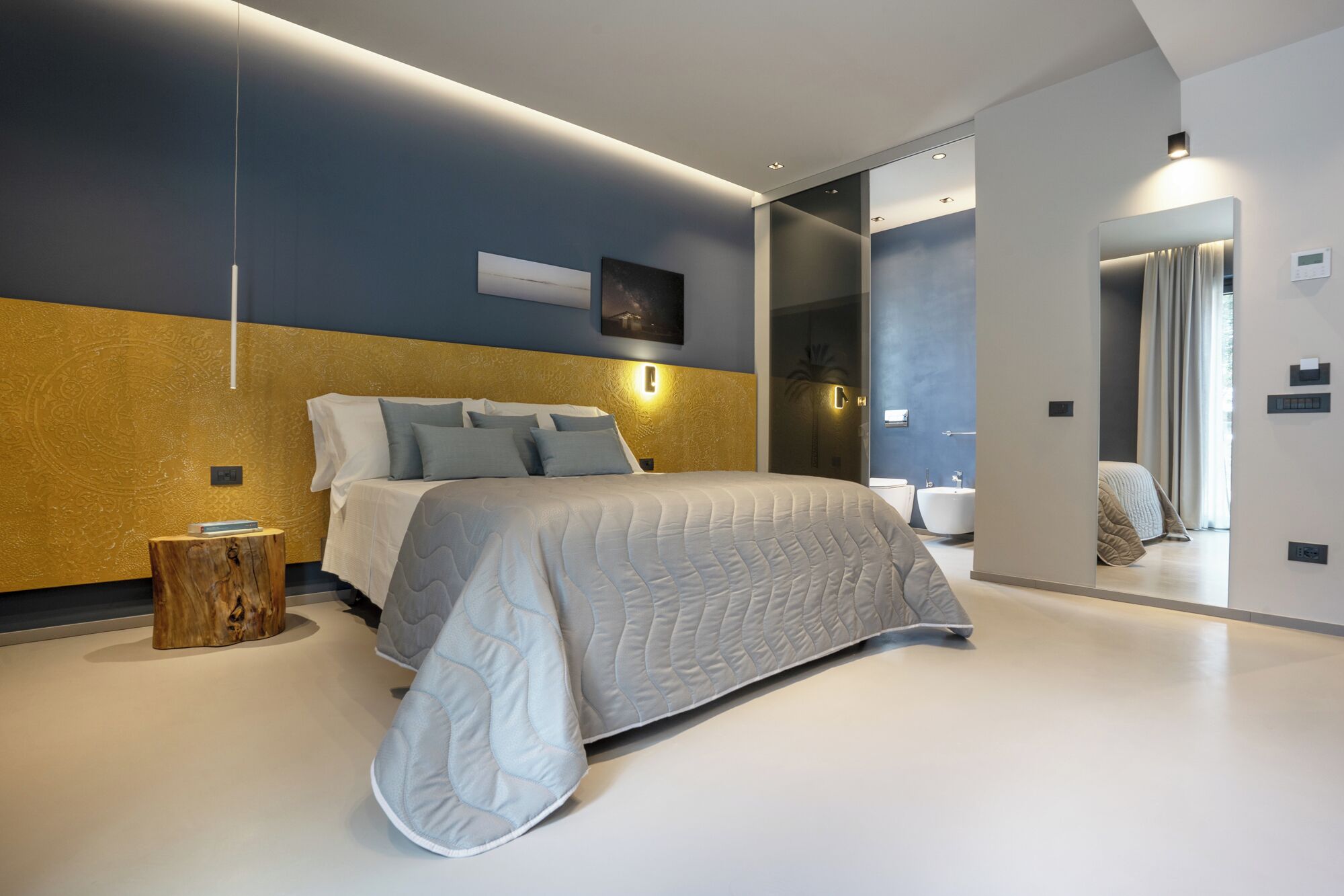 Een moderne slaapkamer met een groot bed, nachtkastjes en een spiegel.