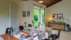 Een eetruimte met een houten tafel voor vier personen, omringd door stoelen, met uitzicht op groen.
