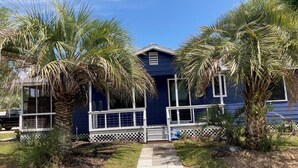 Una casa de dos pisos con fachada azul, ventanas blancas y un porche delantero.