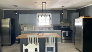 Una cocina moderna con armarios grises, una isla de madera y electrodomésticos de acero inoxidable.