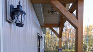 A covered patio area with stone pillars and a wooden beam structure. - Secluded and spacious Barndominium close to 2 Ski Resorts and many attractions! (Factoryville)