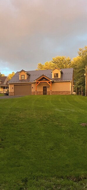 A two-story house with a front garage and a well-maintained lawn. - Secluded and spacious Barndominium close to 2 Ski Resorts and many attractions! (Factoryville)
