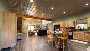 A spacious kitchen with wooden cabinets and a dining area with two wooden chairs. - Secluded and spacious Barndominium close to 2 Ski Resorts and many attractions! (Factoryville)
