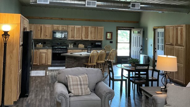 A spacious loft with a high ceiling, wooden staircase, and a kitchen area. - Secluded and spacious Barndominium close to 2 Ski Resorts and many attractions! (Factoryville)