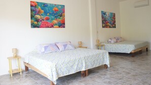 Dos camas individuales con ropa de cama estampada, mesitas de noche de madera y lámparas fijadas a la pared.