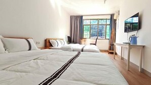 Quarto de hotel com duas camas, televisão, escrivaninha e janela com cortinas.