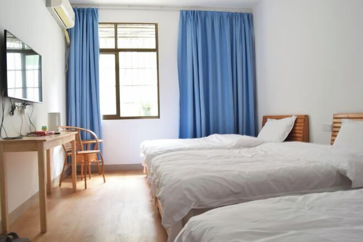 Habitación de hotel con dos camas, un escritorio, una silla y un televisor.