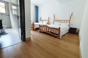Una habitación de hotel moderna con dos camas de madera, un ventanal grande y una puerta de cristal que da al baño.