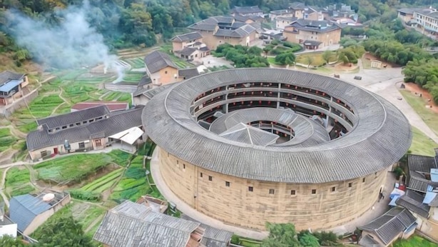 Um edifício circular com vários andares, rodeado por edifícios residenciais e vegetação.