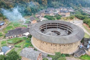 Un edificio circular con varios pisos, rodeado de edificaciones residenciales y vegetación.