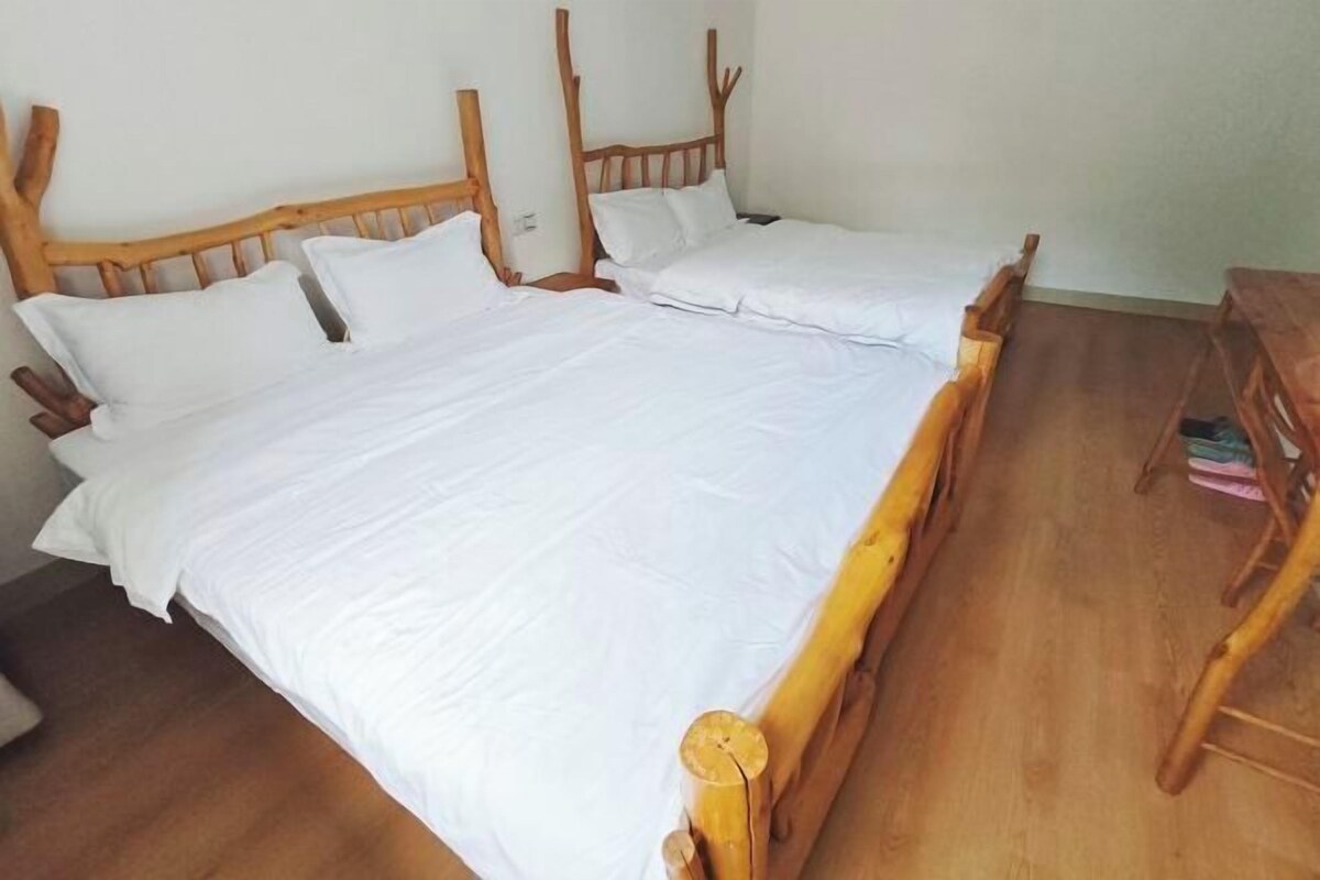 Una habitación con una cama de madera, ropa de cama blanca y una silla de madera.