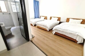 Habitación de hotel con dos camas, un baño y una puerta de vidrio que da a la zona de la ducha.