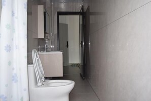 Un baño moderno con inodoro, lavamanos y zona de ducha.