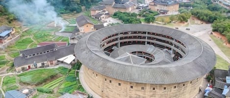 A circular building with multiple floors, surrounded by residential houses and greenery.