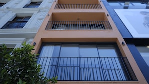 A multi-story building with balconies, large windows, and a tree in the foreground. - Rue Rooms (Fethiye)