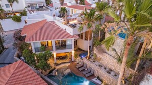 A residential property with a swimming pool, a covered patio, and a stone wall.