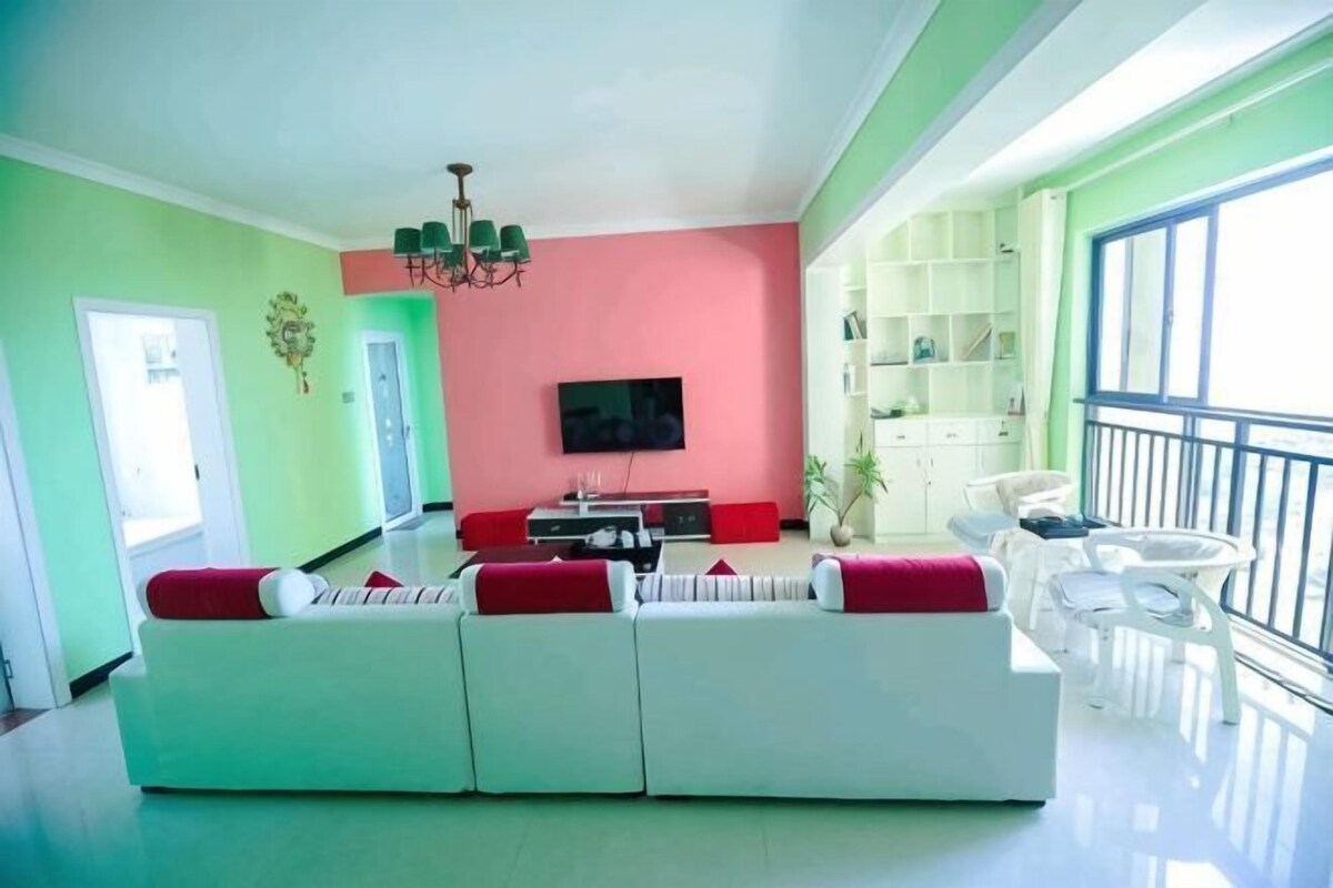 A living room with a sofa, a television, and a balcony.