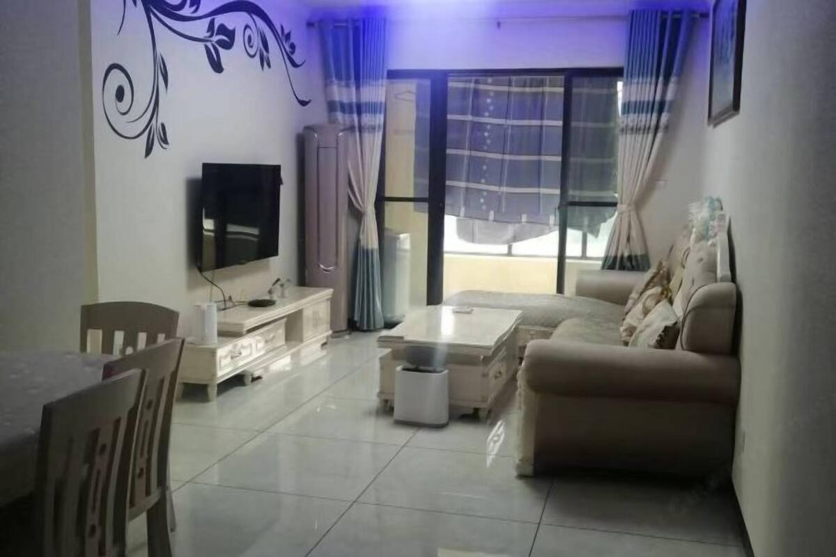 A living room with a sofa, TV, dining table, and chairs.