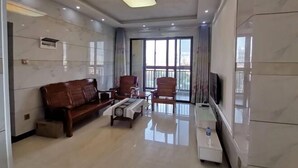 A modern living room with a sofa, chairs, a coffee table, and a TV. - Youtian Yangsheng Holiday Apartment (Beihai)