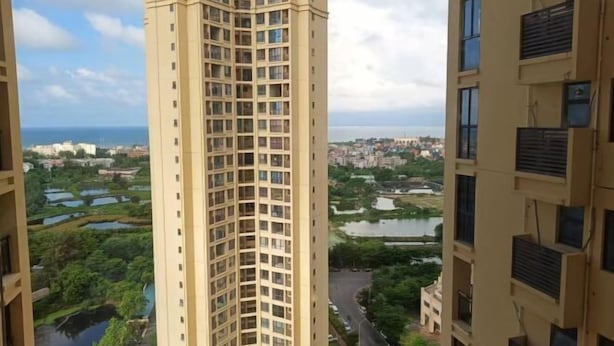 A high-rise building with multiple floors, surrounded by greenery and a body of water. - Youtian Yangsheng Holiday Apartment (Beihai)