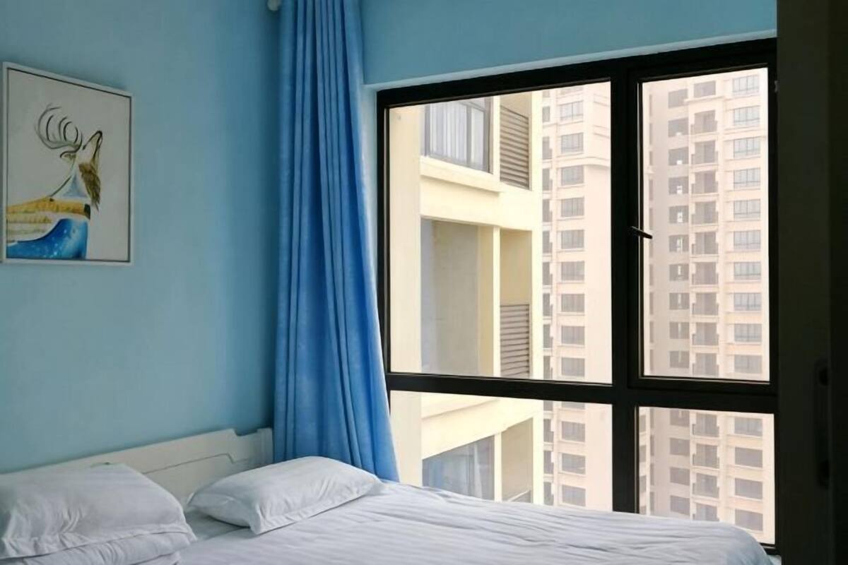 A bedroom with a bed, a window, and a view of a building.