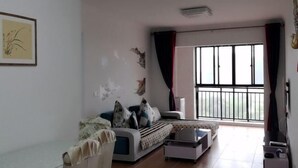 A living room with a sofa, a coffee table, and a large window with curtains. - Youtian Yangsheng Holiday Apartment (Beihai)
