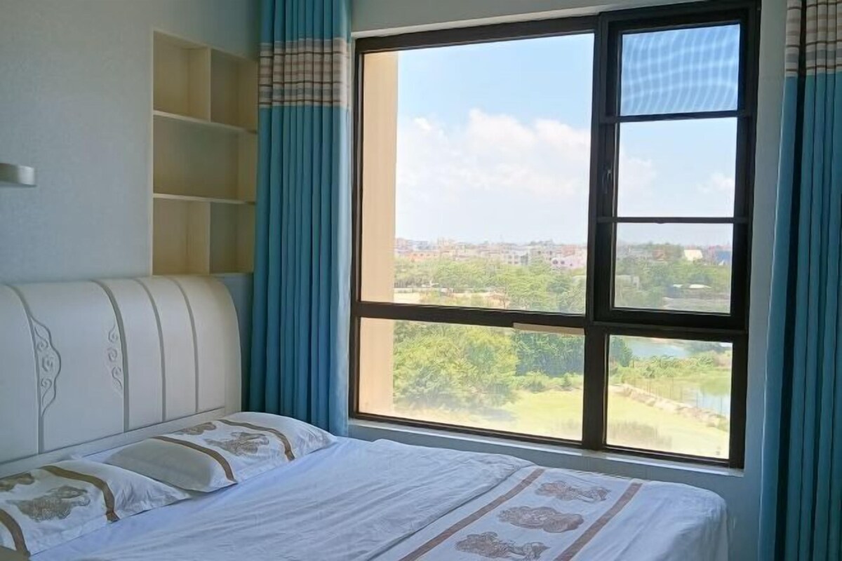A bedroom with a large window, a bed, and a built-in shelf unit.
