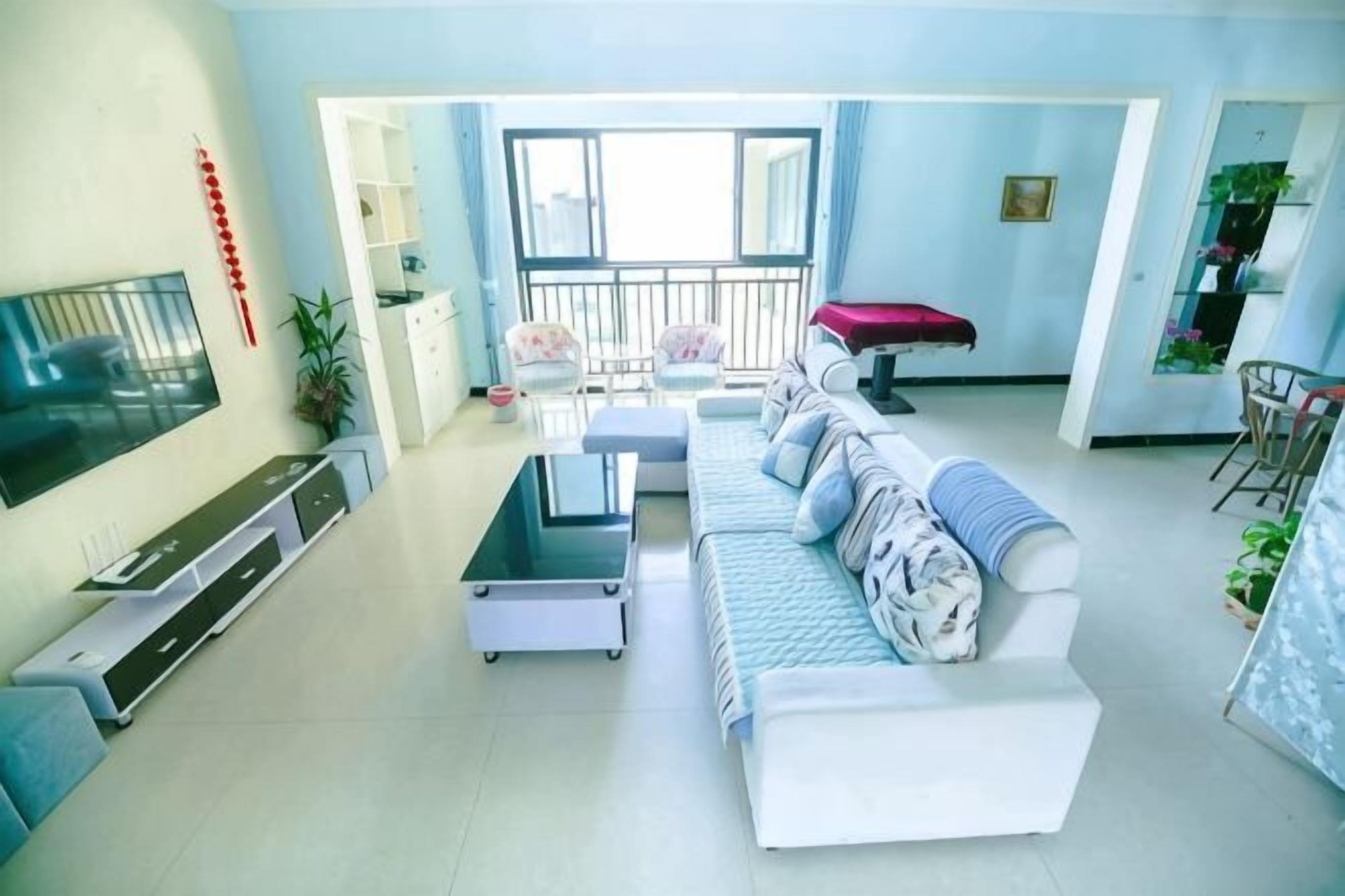 Una sala de estar con sofá, televisor y balcón.