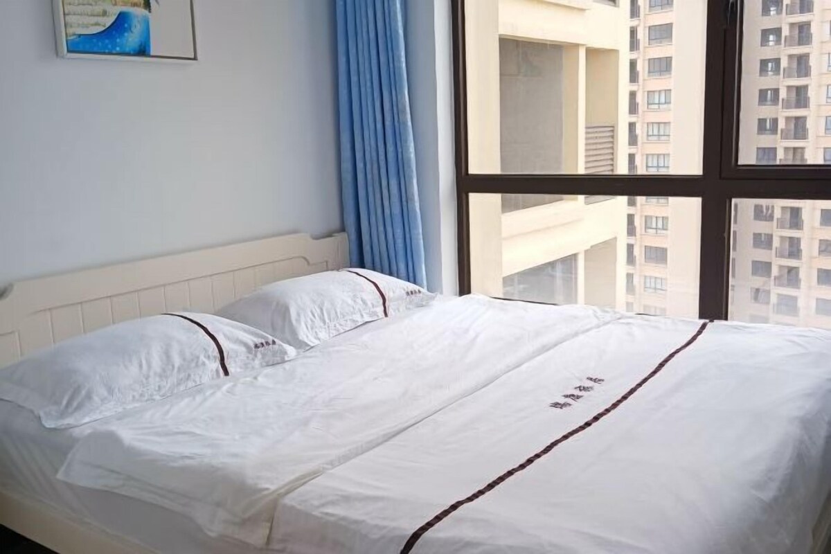A bed with white bedding and a window with a view of a building.