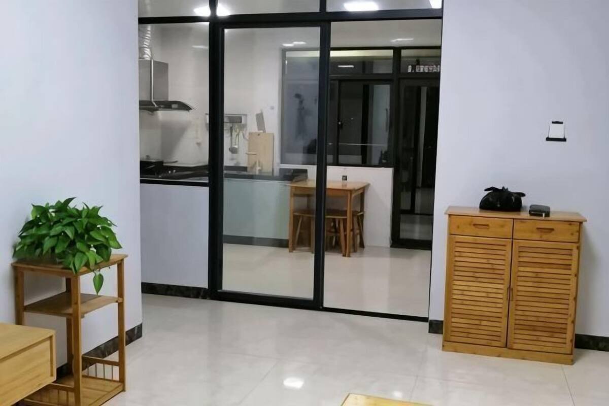 A modern kitchen with a dining area, a wooden cabinet, and a plant.