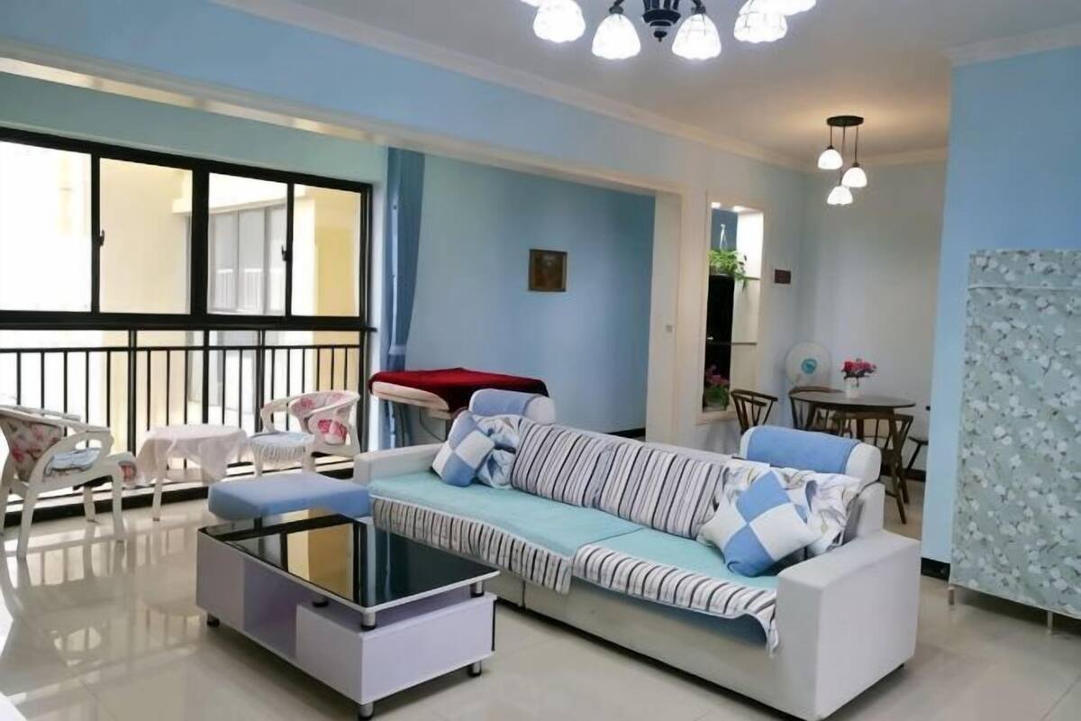 A living room with a sofa, a coffee table, and a dining area with chairs and a table.