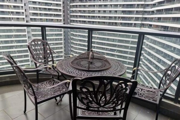 A balcony with a round table and four chairs, overlooking a cityscape.