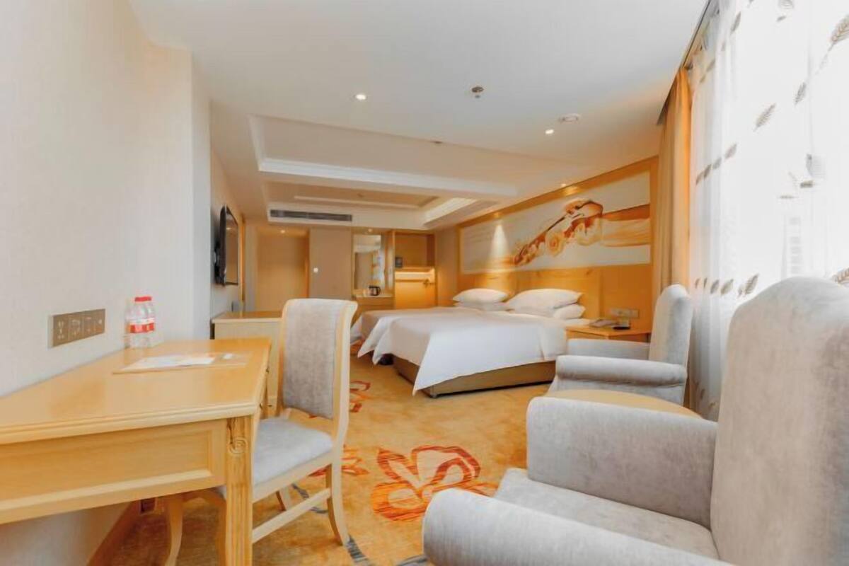 Una habitación de hotel con una cama, dos sillones, un escritorio y una televisión.