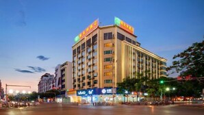 Un hotel de varios pisos con fachada moderna, múltiples balcones y señalización iluminada.