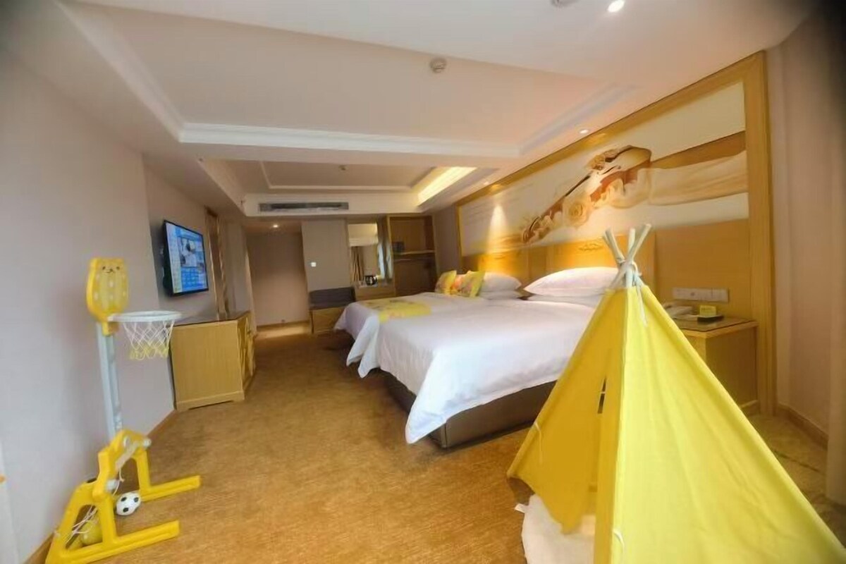 A hotel room with a bed, a television, a yellow tent, and a basketball hoop.