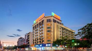 A multi-story hotel with a prominent sign on the top, a large entrance with a ramp, and a busy street in front.