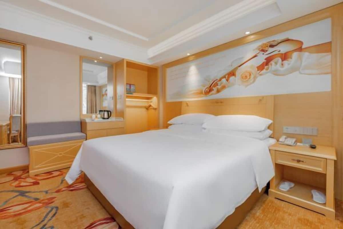 Una habitación de hotel con una cama grande, una mesita de noche, un espejo y una obra de arte colgada en la pared.