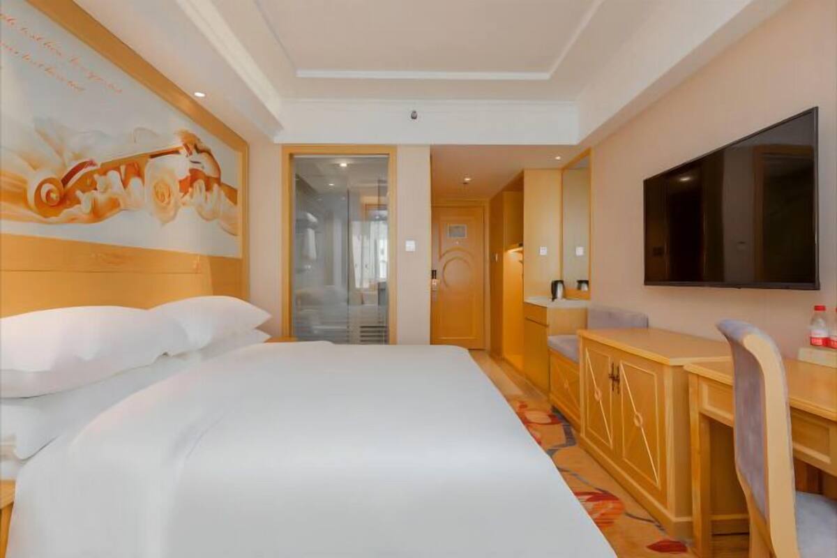 Una habitación de hotel con una cama, un escritorio, una silla, un televisor y una puerta que da a otra habitación.