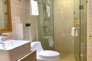 A modern bathroom with a glass-enclosed shower, a white sink, and a toilet.