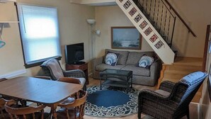 A spacious living room with a dining area, a staircase, and a ceiling fan.